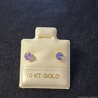 Front view of two round tanzanite stones set in 10K gold studs on a white display card marked '10 KT. GOLD'