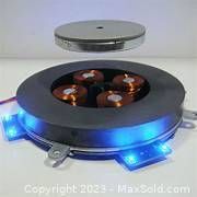 Levitating circular magnet disc over round base with copper coils and blue LED lights on.