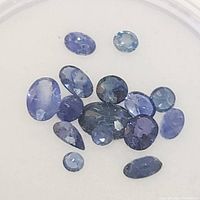 Top view of mixed shaped and sized blue sapphire gemstones in various blue hues.
