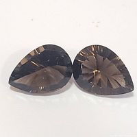 Pair of pear-shaped faceted Smokey Quartz gemstones displayed on a white background to showcase color, cut, and clarity.