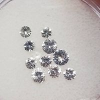 Ten loose round-cut white sapphire gemstones on a white background, showing sparkle and clarity.