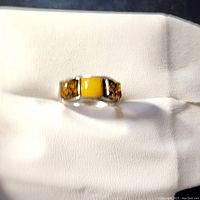 Front view of silver ring with amber and resin insets placed on white fabric.