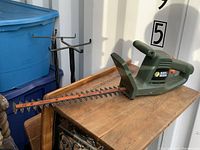 Side view of Black & Decker electric hedge trimmer showing full 16-inch blade and green plastic body.