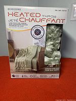 Front box view showing product name, image of the throw with green fair isle pattern, and faux fur visible through the box window.