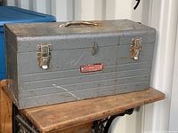 Exterior view of large vintage gray metal toolbox with rust and paint wear