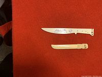 Top view of both letter openers laid on red fabric, showing full length of blades and handles.