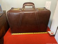 Front view of vintage handmade brown leather Condotti briefcase showing handle, stitching, and brass combination locks.