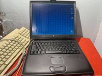 Open Apple Macintosh G3 PowerBook laptop powered on showing desktop screen with external keyboard in background
