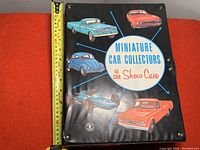 Front cover of the vintage miniature car collectors showcase folder, showing colorful illustrations of classic cars and the product title.
