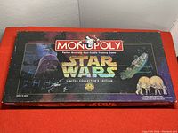 Top view of the Monopoly game box featuring Star Wars artwork including Darth Vader, Millennium Falcon, and AT-AT walkers. The box is marked as Limited Collector's Edition.