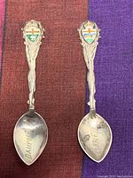 Two vintage sterling silver spoons with enamel crests and Indigenous-themed handles, engraved with 'Danville' and 'Edmonton'.