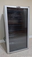Front view of the Danby wine cooler showing glass door with black frame and metal racks inside.