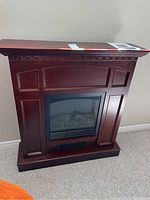 Full front view of electric fireplace showing wood mantel and glass fireplace insert with ember bed.