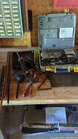Serpentine saw, caulking devices, hand cranked drill, copper pipe, cookie sheet on workbench