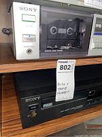 Photo showing two Sony stereo components stacked on a shelf. Top is cassette deck TC-FX2 with visible cassette compartment, and bottom is CD player CDP-295 with power button and pulse display.