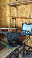 Photo showing the mitre box saw on wooden frame with Mastercraft hole saw set in case and Houseworks screwdriver case on table