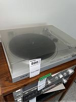 Full view of the Sony turntable on a wooden surface, showing the dust cover and control labels.
