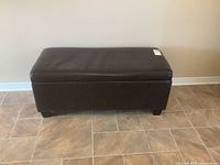 Front view of the dark brown vegan leather blanket box sitting on tile floor against wall