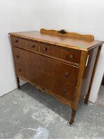 Front angle of the vintage wooden buffet/server showing four drawers and carved bottom detail.