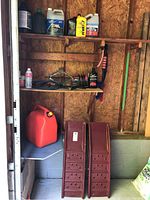 Photo shows two red metal car ramps, red plastic jerry can on shelf.