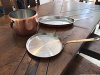 Copper ice bucket, copper fish pan, and heavy copper frying pan arranged on a wooden table, showing general condition and size relation