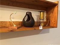 Photo showing full lot including two brass hooks, pottery planter or bird house and brass lantern on a wooden shelf