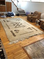 Full view of large plush rug on wood floor with visible Aztec design and fringed edges