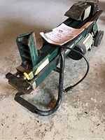 Front angle view of green Yardworks electric log splitter with owner's manual on top