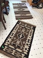 Photo showing both rugs lying flat on a white tiled floor, highlighting their size, colors, and patterns including frayed fringe.