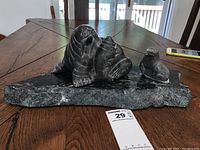 Front view of soapstone carving showing walrus with pup on stone base and separate pup carving on the right.