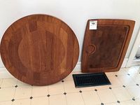 Round wood slab approx 20 inches diameter next to rectangular wooden tray showing size comparison and wood finish
