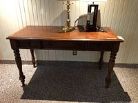 Front view of wooden desk with three drawers and turned legs