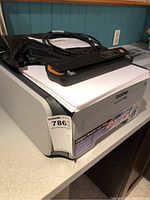 Brother HL-2170W laser printer with label on front and some toner packaging on top, placed on countertop.
