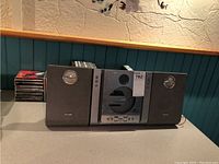 Philips MCM240 Micro System with central CD player and two speakers on either side, aged with some wear. Assortment of CDs placed near the system.