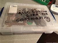 Plastic storage box labeled “misc. cutting dies for cardmaking” showing contents inside.