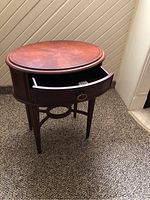 Full view of the round Bombay end table with a single open drawer showing shape and finish.