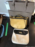 Three purses shown together: large taupe Danier leather tote, yellow purse with VW initials, off-white and black Nine West purse.