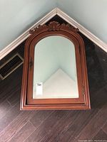 Full view of the wooden medicine cabinet showing the carved frame surrounding the beveled mirror door.