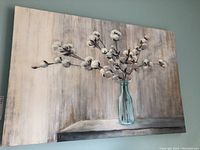 Full view of the stretched canvas print showing cotton branches in a vase against a muted wood texture background.