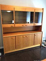 Full view of the two-piece teak china cabinet showing upper glass doors and lower solid doors.