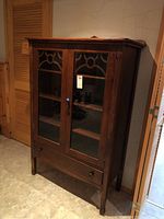 Front view of vintage wood hutch showing double glass doors with decorative wooden trims and dovetail drawer below