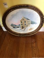 Full view of the oval painting showing the winter landscape scene and detailed frame.