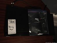 Sony Blu-Ray player with label indicating Blu-Ray Player, remote control in plastic bag on top.