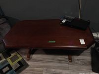 Full view of wood veneer coffee table showing rectangular top with beveled edges and two pedestal style legs on each side.