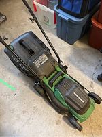 Full view of the electric lawn mower showing the grass catcher bag, handle, wheels, and body.