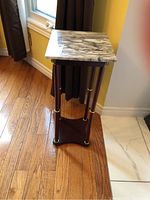Pedestal table showing front and side view, wooden base and marble top visible