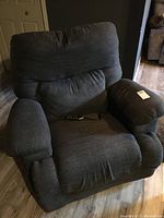 Front view of gray electrical recliner chair with remote control on seat cushion.