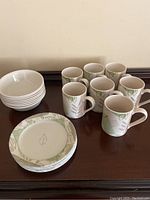 Complete breakfast set arranged with coffee mugs, shallow bowls, and small plates on a wooden surface.