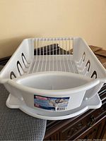White plastic dish drying rack showing utensil holder and plate slots, with Sterilite label visible