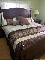 Full view of bed frame, bedding, mattress and one bedside lamp